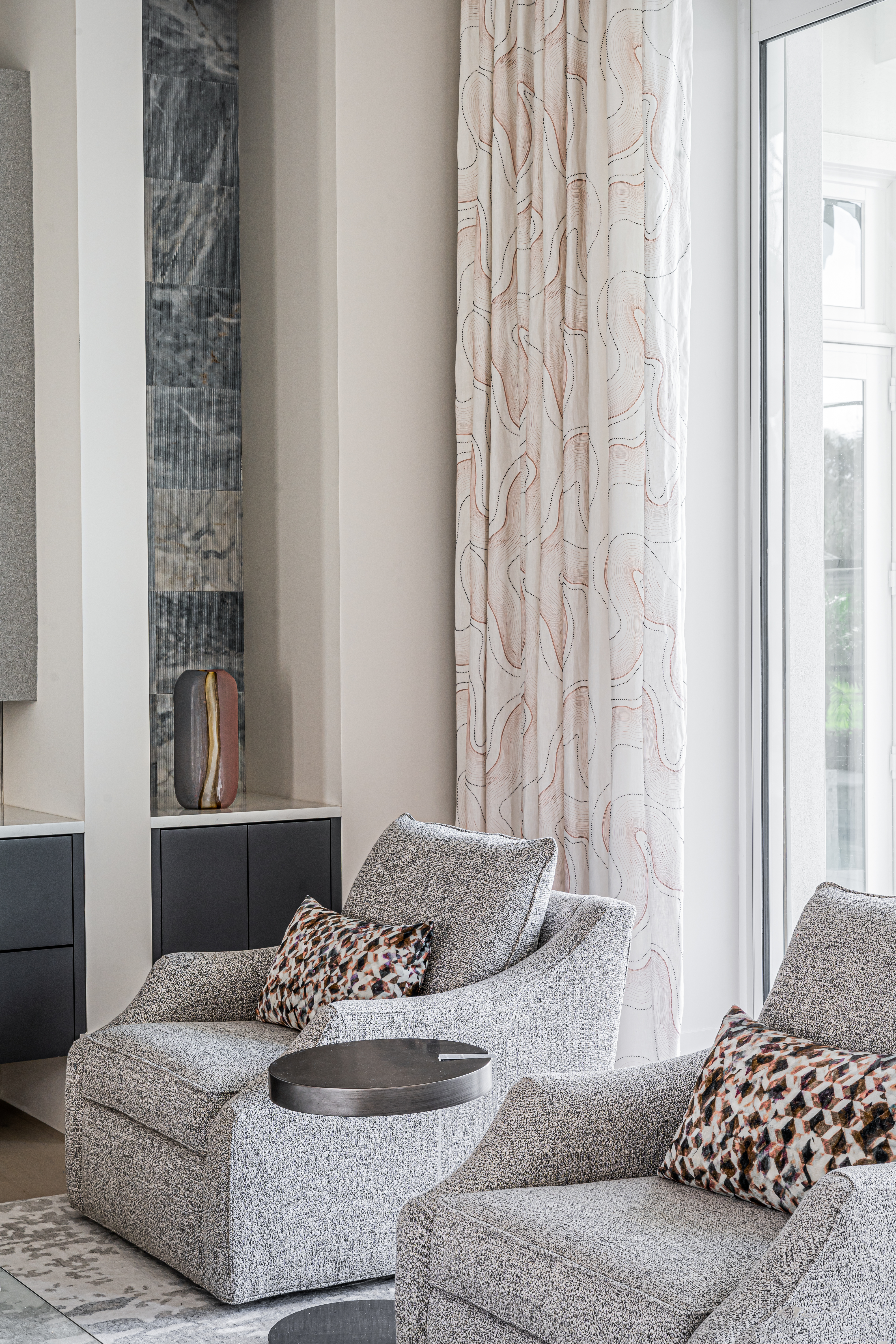 A coastal contemporary living room swivel chair design with a blush palette, designed by Florida interior designer Brooke Meyer of Gulfshore Interior Design